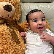 Stefano joined the competition — help win amazing prizes! baby, teddy_bear, couch, smile, child, plush_toy, white_shirt, striped_pants, happy, indoor, cute, infant, furniture, cozy, soft_toy, portrait, sitting, light_gray, bow, fun