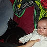 baby, infant, child, black_cat, cat, pet, indoors, portrait, sitting, lying_down, white_clothing, blanket, cushion, red_cushion, arm, hand, furniture, home, animal, cozy