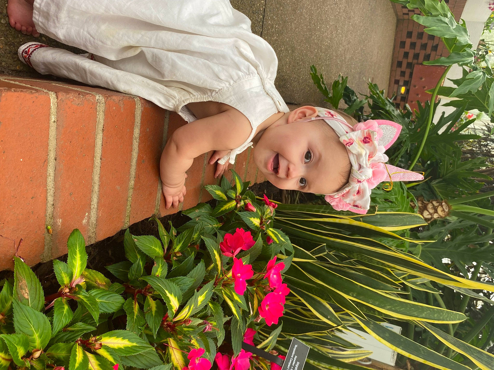 Phoenix is registered to the contest to win money with this photo: annual_plant, baby, baby_toddler_clothing, bouquet, child, cut_flowers, floral_design, flower, flower_arranging, flowering_plant, grass, happy, head, headwear, people_in_nature, person, petal, plant, smile, terrestrial_plant