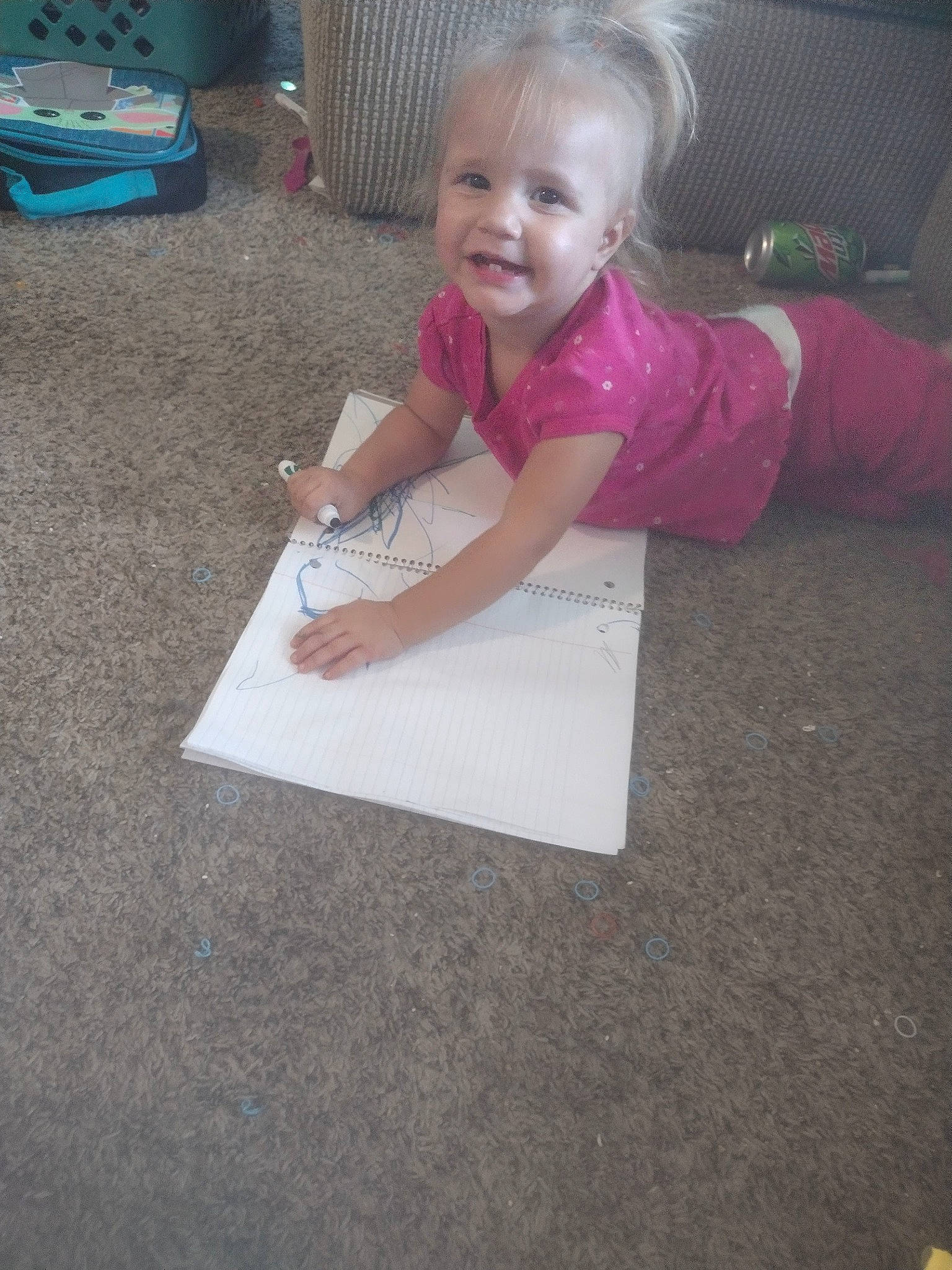 Lilly is registered to the contest to win money with this photo: asphalt, baby_toddler_clothing, child, floor, flooring, fun, grass, magenta, person, pink, play, road_surface, room, sidewalk, sitting, smile, t_shirt, toddler, vacation, wood