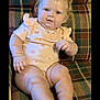 Briella joined the competition — help win amazing prizes! baby, child, infant, couch, plaid, onesie, socks, blue_eyes, cute, chubby, indoor, portrait, seated, furniture, smiling, person, young, skin, face, hand