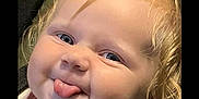 Briella joined the competition — help win amazing prizes! baby, child, tongue_out, curly_hair, car_seat, straps, playful, blue_eyes, close_up, smiling, infant, cute, face, skin, person, young_child, indoors, seatbelt, expression, head