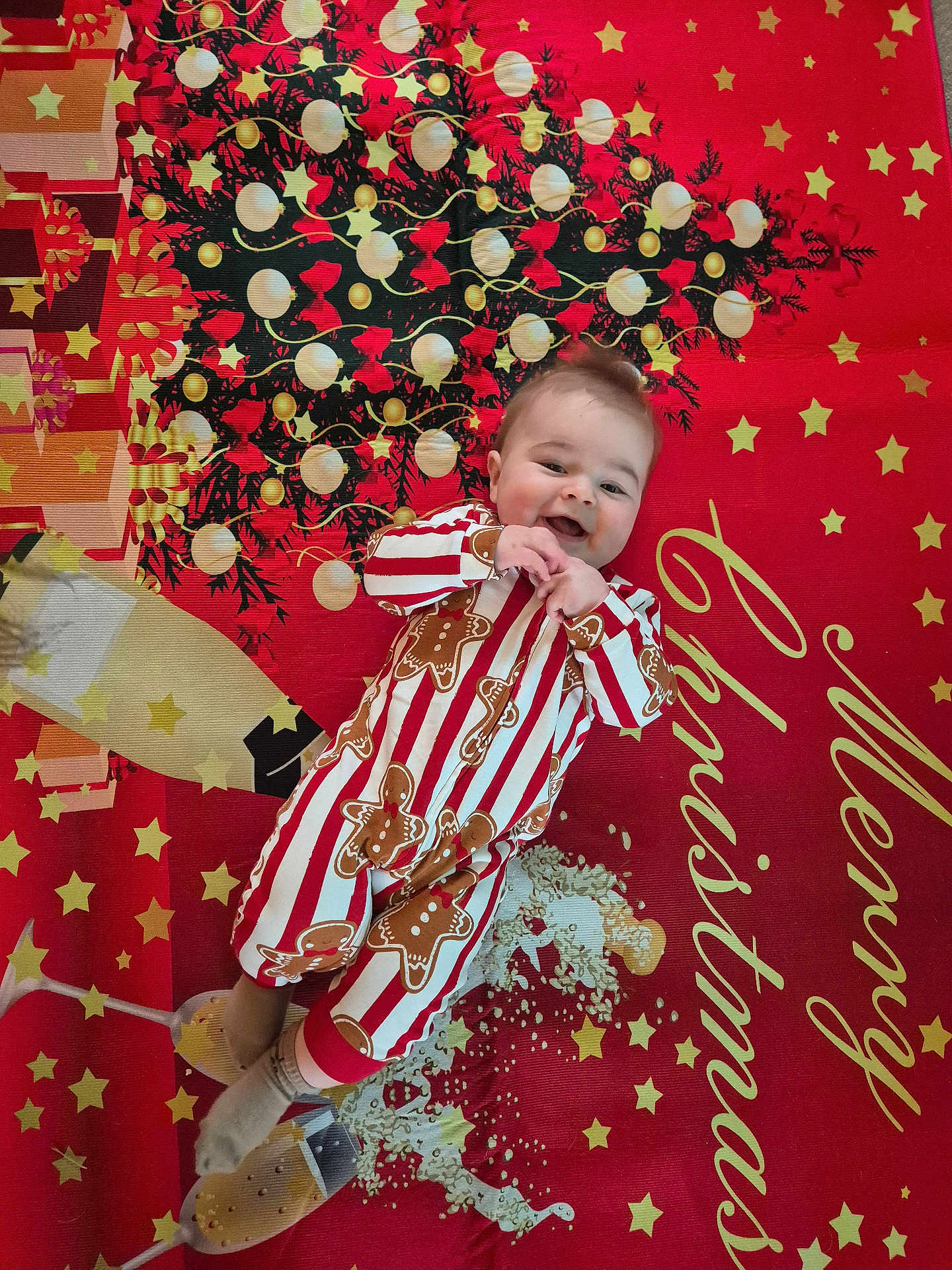 Archie is registered to the contest to win money with this photo: baby, child, pajamas, gingerbread, christmas, holiday, blanket, smile, happy, face, festive, tree, decorations, stars, champagne, glasses, red, white, pattern, lying_down