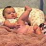 Megan is registered to the contest to win money with this photo: baby, infant, child, pillow, blanket, floral_pattern, pink_clothing, soft_texture, indoor, cute, chubby, relaxed, person, skin, face, hand, foot, leg, expression, comfort