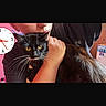Stitch is registered to the contest to win money with this photo: cat, person, indoor, black_cat, yellow_eyes, whiskers, close_up, holding, clock, arm, face_partial, casual, home, furniture, wall, sitting, pet, fur, human_hand, portrait