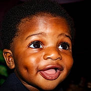 Kieran participe au concours pour gagner de l'argent avec cette photo : child, face, smile, happy, close_up, young_child, dark_background, eyes, mouth, dimples, portrait, curly_hair, skin, expression, person, cute, innocence, joy, head, baby