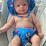 baby, infant, child, blue_hat, mickey_mouse, drool, baby_seat, cushion, patterned_fabric, bare_chest, cute, smiling, indoors, comfort, seat_belt, plush, young_child, sun_hat, diaper_cover, relaxed