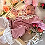 baby, infant, pink_clothing, headband, bow, flower, floral_arrangement, lace, sock, cute, sleepy, indoors, portrait, soft_lighting, newborn, resting, decorative, wooden_frame, fabric, child