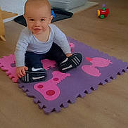 Tyméo a rejoint le concours — aidez-le/la à gagner de superbes lots ! baby, child, indoor, playmat, toy, sneakers, floor, smile, person, head, clothing, pants, footwear, expression, room, plastic_toy, curious, seated, young, light