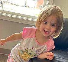 Brenda is registered to the contest to win money with this photo: bangs, blond, brown_hair, cheek, child, facial_expression, finger, fun, gesture, happy, joy, leisure, person, sitting, sleeve, smile, surfer_hair, t_shirt, thigh, thumb