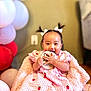 Eleanor is registered to the contest to win money with this photo: baby, child, girl, pigtails, bows, pink_dress, strawberry_pattern, blanket, balloons, indoor, happy, smiling, holding, wooden_sign, sitting, cute, portrait, infant, celebration, soft_texture