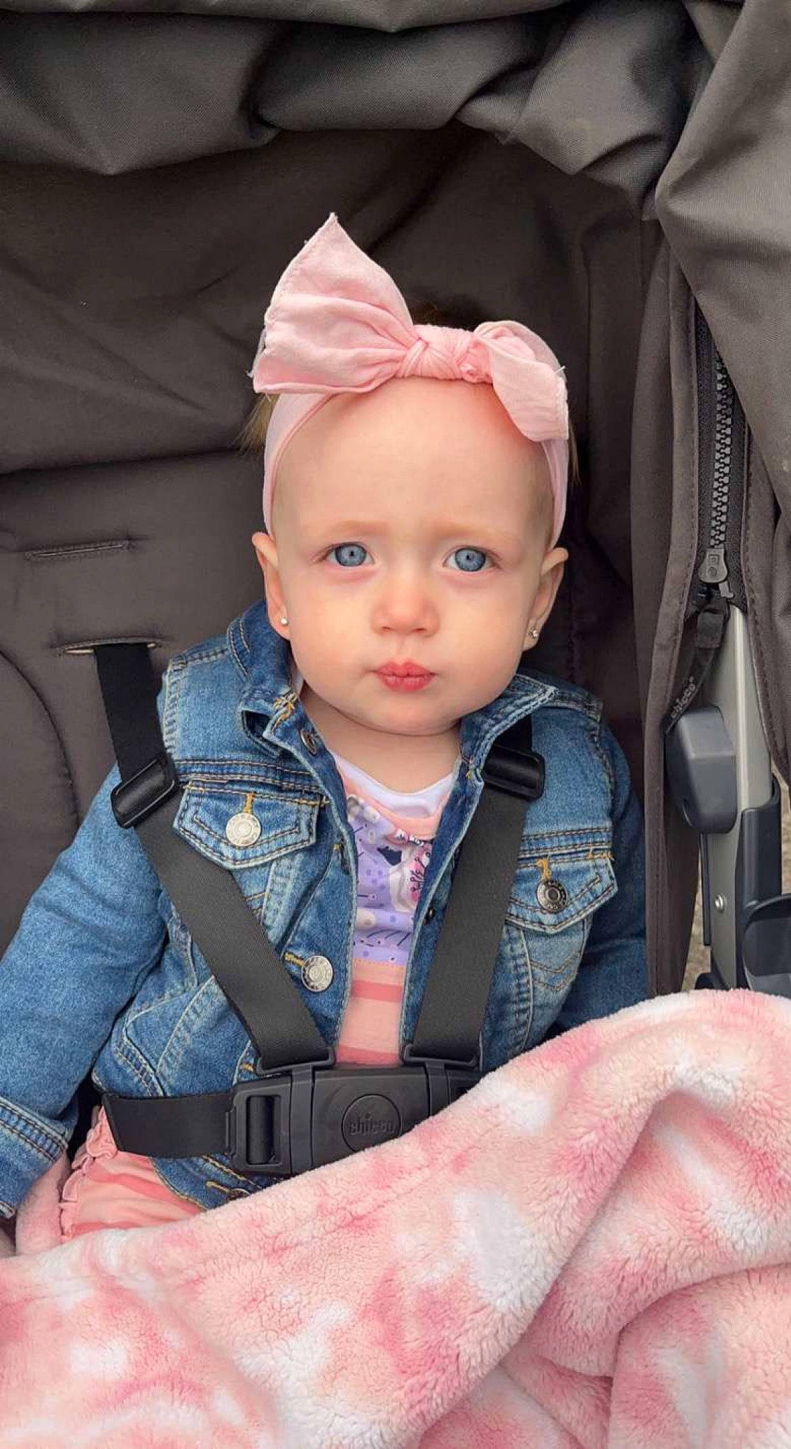 Lila is registered to the contest to win money with this photo: baby, baby_carriage, baby_products, baby_toddler_clothing, beanie, cap, cheek, child, comfort, eyelash, facial_expression, fashion_accessory, fun, happy, lip, person, pink, sitting, skin, sleeve