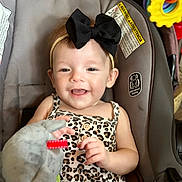 Lillian joined the competition — help win amazing prizes! baby, child, smiling, headband, black_bow, leopard_print, top, denim_shorts, car_seat, toy, soft_toy, hand, happy, infant, cute, indoors, seatbelt, closeup, portrait, playful