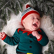 Lucyano a rejoint le concours — aidez-le/la à gagner de superbes lots ! baby, infant, smiling, christmas_hat, elf_costume, fur_rug, pine_branches, faux_snow, green_outfit, red_trim, lying_down, happy, adorable, portrait, seasonal, cute, newborn, festive, infant_face, cozy