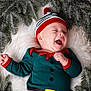 baby, infant, smiling, christmas_hat, elf_costume, fur_rug, pine_branches, faux_snow, green_outfit, red_trim, lying_down, happy, adorable, portrait, seasonal, cute, newborn, festive, infant_face, cozy