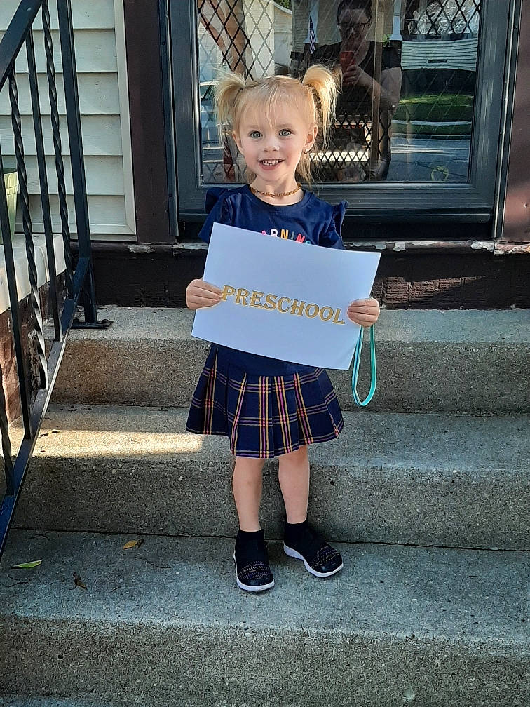 Gemma is registered to the contest to win money with this photo: child, clothing, costume, design, joy, pattern, person, photography, plaid, school_uniform, sitting, snapshot, standing, tartan, toddler, uniform
