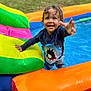 Lorenzo is registered to the contest to win money with this photo: child, toddler, smiling, wet_hair, pool, inflatable_pool, colorful, shark_shirt, water, outdoor, summer, playful, happy, reaching_hand, swimwear, grass, fun, daytime, person, inflatable_toy