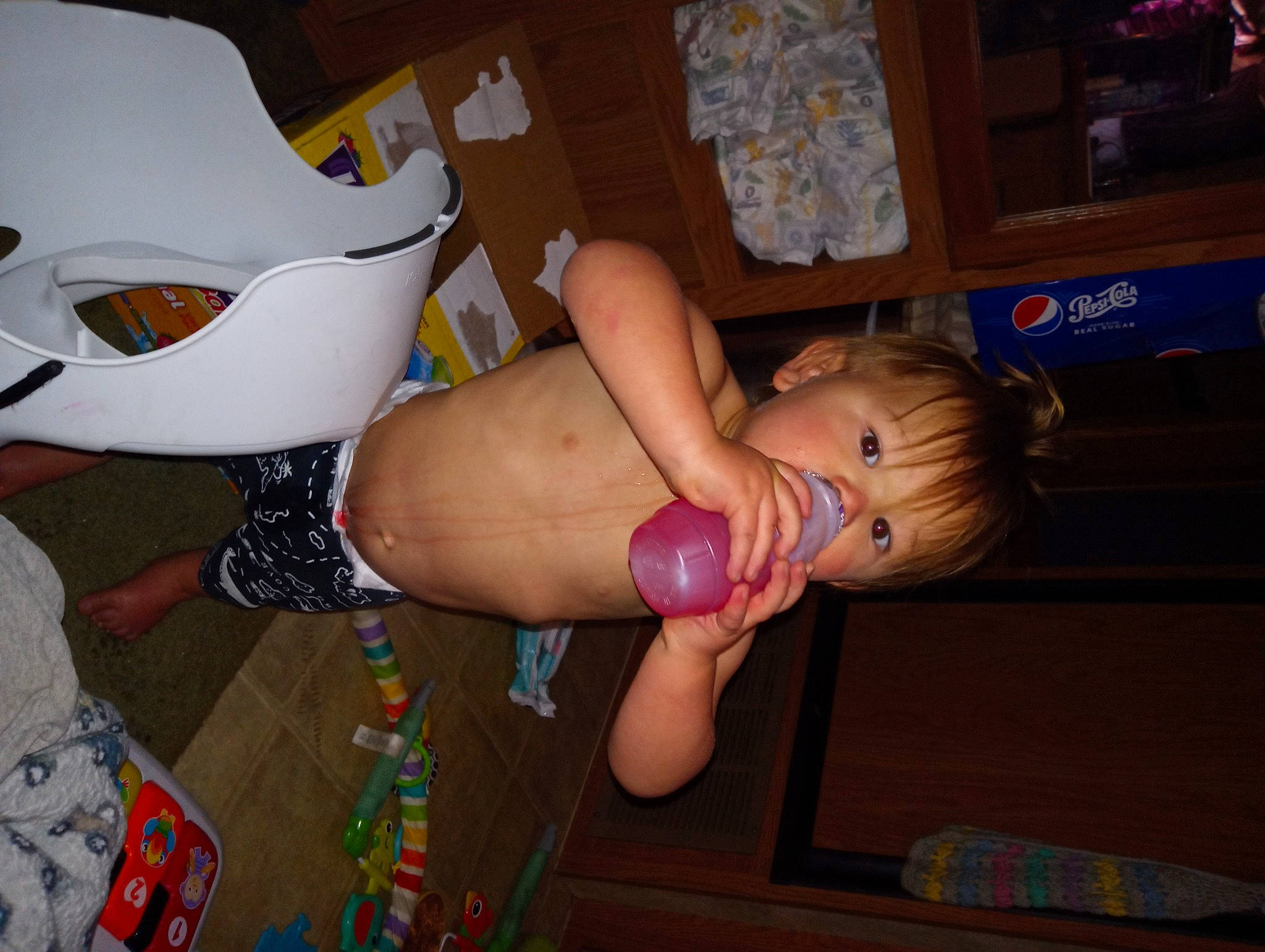 Tega is registered to the contest to win money with this photo: abdomen, chest, child, finger, flooring, foot, fun, human_leg, knee, lap, mouth, party, party_supply, person, sandal, swimwear, thigh, thumb, toddler, toy