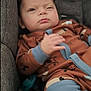 baby, infant, car_seat, onesie, brown_clothing, blue_trim, animal_prints, face, expression, winking, hand, furniture, fabric, indoor, child, cute, cozy, seat, person, portrait