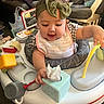 Alicia is registered to the contest to win money with this photo: baby, child, headband, bow, toy, activity_center, tissue_box, indoor, play, smiling, clothing, bib, furniture, blanket, chair, carpet, person, cute, infant, home