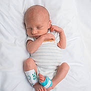 Myles is registered to the contest to win money with this photo: newborn, baby, sleeping, infant, onesie, white_blanket, foot_brace, peaceful, cute, small, human, child, portrait, lying_down, resting, soft, skin, head, hands, feet