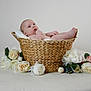Roseabella is registered to the contest to win money with this photo: baby, basket, flower, white_flower, pastel_flower, infant, skin, hand, foot, face, curious, lying_down, soft_texture, blanket, woven, indoor, portrait, cute, peaceful, neutral_background