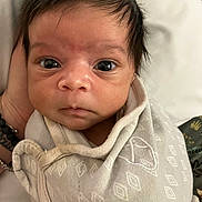 Lorenzo is registered to the contest to win money with this photo: baby, infant, swaddle, wrapped, face, eyes, hand, clothing, newborn, portrait, expression, cute, person, skin, hair, indoors, closeup, soft, fabric, resting