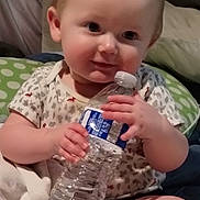 Jeremiah joined the competition — help win amazing prizes! baby, infant, water_bottle, cute, smiling, red_hair, sitting, blanket, pillow, indoor, child, holding, foot, clothing, onesie, person, skin, hand, face, relaxing
