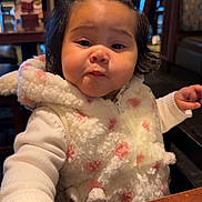 Kataleya is registered to the contest to win money with this photo: baby, background_people, black_hair, booth, child, close_up, cozy, cute, expression, face, fluffy_jacket, hands, indoor, menu, pink_bows, portrait, pout, restaurant, toddler, wooden_table
