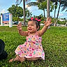 toddler, child, grass, outdoor, park, palm_trees, pink_dress, bows, happy, smiling, summer, nature, greenery, sunny, baby, sitting, cute, playful, daytime, casual_clothing
