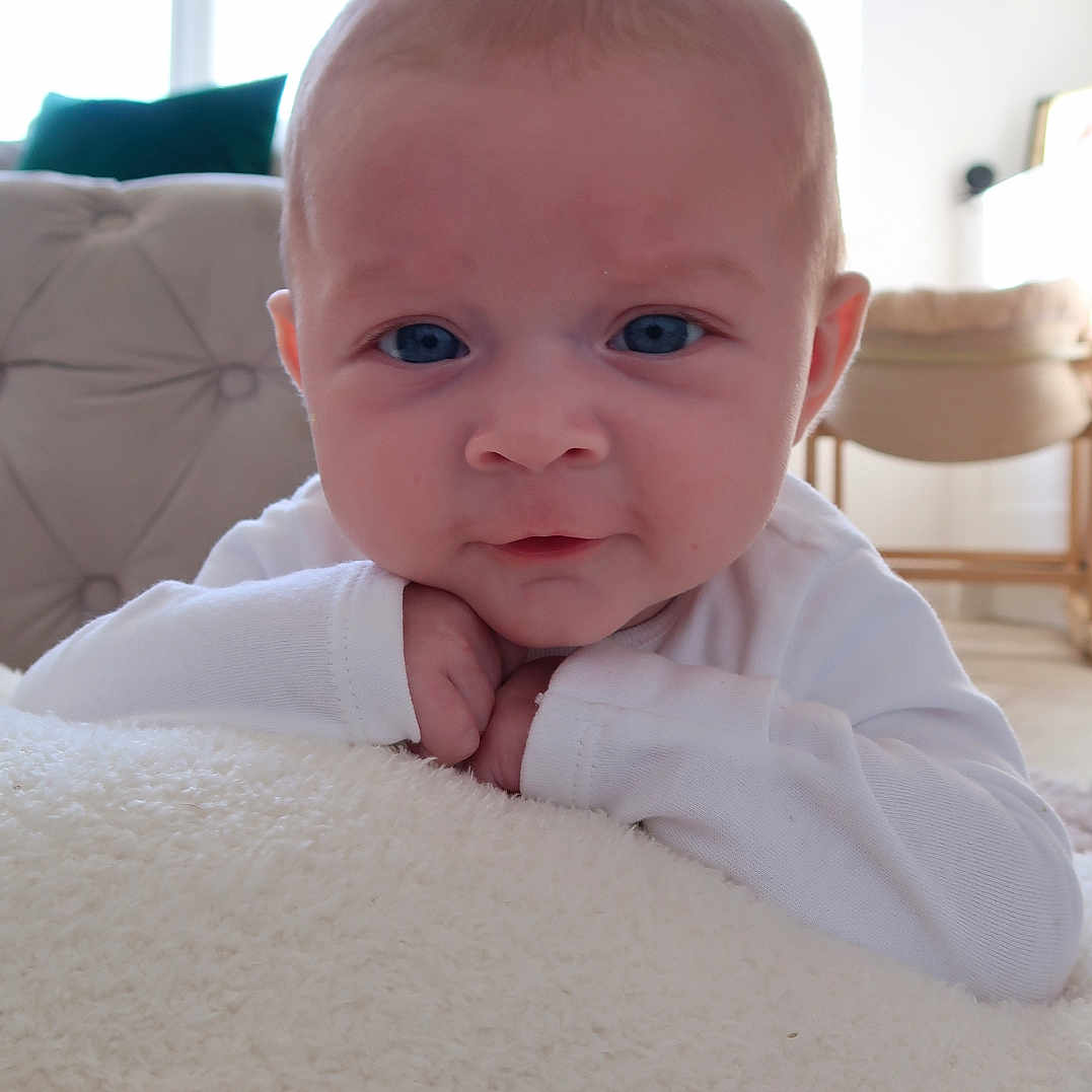 Peony joined the competition — help win amazing prizes! baby, blanket, blue_eyes, child, closeup, cozy, curious, cushion, face, furniture, hands, head, indoors, infant, portrait, resting, soft_light, white_clothing, window, young