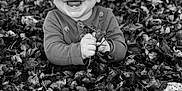 Asher is registered to the contest to win money with this photo: baby, child, smiling, autumn, leaves, outdoor, nature, portrait, black_and_white, happy, cute, infant, fall, season, hands, face, clothing, person, ground, tree
