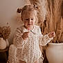 Lou participe au concours pour gagner de l'argent avec cette photo : child, toddler, lollipop, hair_buns, curious, indoors, soft_lighting, neutral_colors, dried_plants, decor, vase, long_sleeve, romper, cute, portrait, standing, young_child, innocence, cozy, home