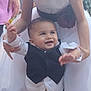 baby, child, girl, toddler, dress, tuxedo, smiling, outdoor, person, family, holding, happy, celebration, footwear, white_dress, vest, young, cute, supporting, socks