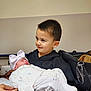 David is registered to the contest to win money with this photo: child, baby, newborn, boy, sleeping, hat, bow, hospital, indoor, person, holding, black_bag, clothing, cute, portrait, family, love, smile, sibling, toddler