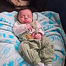 baby, blanket, cartoon_character, child, clothing, comfort, couch, cozy, cute, face, green_outfit, indoors, infant, person, portrait, resting, sleeping, socks, soft, young