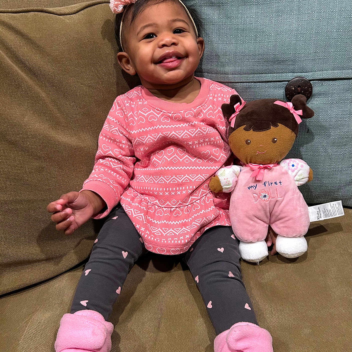 Paitynn joined the competition — help win amazing prizes! toddler, child, smiling, pink_clothing, headband, plush_doll, couch, cushion, indoor, happy, leggings, footwear, toy, person, sitting, cute, baby, portrait, home, cozy