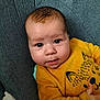 baby, infant, child, yellow_sweater, animal_print, face, eyes, expression, cushion, gray_background, clothing, portrait, resting, indoors, cute, young, person, sitting, soft_texture, closeup