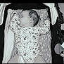 baby, sleeping, pacifier, mickey_mouse, onesie, stroller, cushion, infant, child, resting, cute, clothing, pattern, comfort, relaxation, indoors, monochrome, portrait, peaceful, young