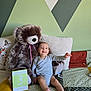baby, teddy_bear, bed, pillow, blanket, milestone_card, wall_art, child, infant, smiling, indoor, soft_toy, clothing, furniture, person, cute, happy, sitting, portrait, home