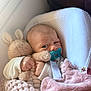 baby, infant, pacifier, toy, stuffed_animal, blanket, cushion, soft_texture, indoor, child, cute, newborn, comfort, sleeping_bag, rest, face, hand, expression, cozy, person