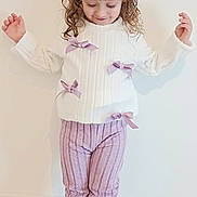 Maitê a rejoint le concours — aidez-le/la à gagner de superbes lots ! child, girl, white_sweater, lilac_bows, curly_hair, hair_clip, pink_pants, striped_pants, black_boots, standing, looking_down, shy_smile, indoor, cream_wall, carpet, full_body, portrait, kids_fashion, ribbon, cute