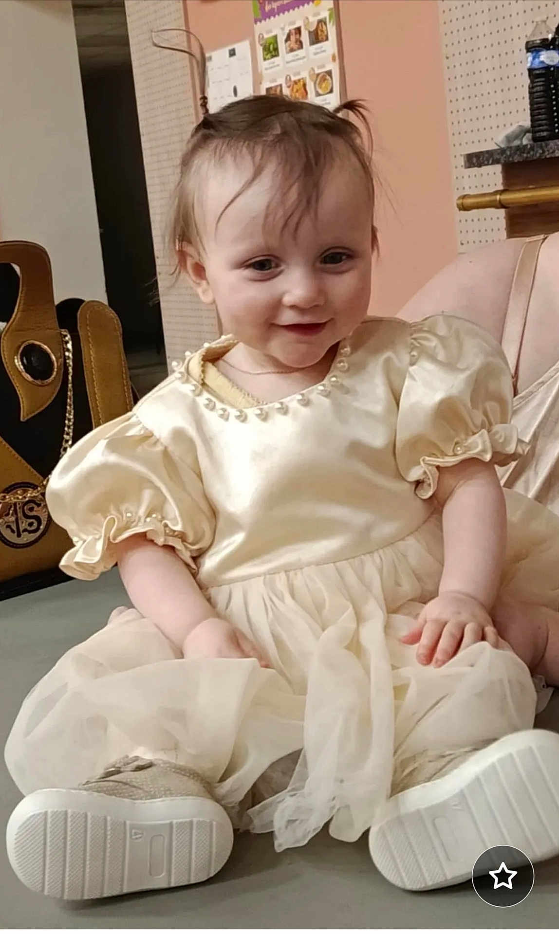 Diana participe au concours pour gagner de l'argent avec cette photo : baby, child, smiling, dress, puffy_sleeves, sitting, indoor, happy, face, hair, footwear, shoes, floor, bag, wall, decor, person, portrait, clothing, cute