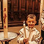 Matheo a rejoint le concours — aidez-le/la à gagner de superbes lots ! child, boy, candle, church, indoors, smile, jacket, wooden_paneling, lighting, religion, proud, young, holding, decorated_candle, floor, person, portrait, warm_colors, standing, event