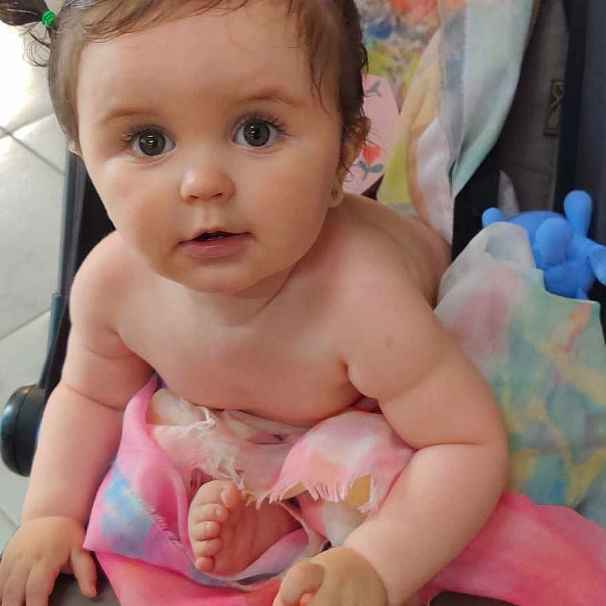 Sofia is registered to the contest to win money with this photo: baby, blanket, child, closeup, colorful, curious, cute, face, foot, hand, indoors, infant, person, pigtails, portrait, seated, skin, soft, stroller, toy