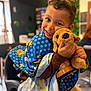 Tom a rejoint le concours — aidez-le/la à gagner de superbes lots ! child, smiling, barber_cape, polka_dots, stars, stuffed_dog, plush_toy, chair, barbershop, indoor, portrait, close_up, happy, candid, brown_hair, hands, toy, seat, clothing, playful