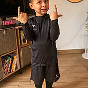Tom participe au concours pour gagner de l'argent avec cette photo : child, boy, smile, portrait, indoor, black_uniform, soccer_cleats, shorts, long_sleeve, socks, hands_up, curly_hair, brown_eyes, living_room, bookshelf, mirror, cabinet, wooden_floor, playful, cute