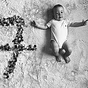 Mylan participe au concours pour gagner de l'argent avec cette photo : baby, infant, blanket, flower_confetti, number_one, black_and_white, portrait, smiling, happy, cute, lying_down, texture, soft, milestone, celebration, one_year, child, indoors, clothing, head