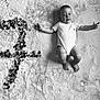 baby, infant, blanket, flower_confetti, number_one, black_and_white, portrait, smiling, happy, cute, lying_down, texture, soft, milestone, celebration, one_year, child, indoors, clothing, head