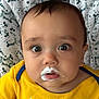 Zachary is registered to the contest to win money with this photo: baby, milk_mustache, yellow_shirt, wide_eyes, infant, expression, face, clothing, patterned_background, seat, child, cute, closeup, portrait, person, indoors, young, sitting, apparel, head